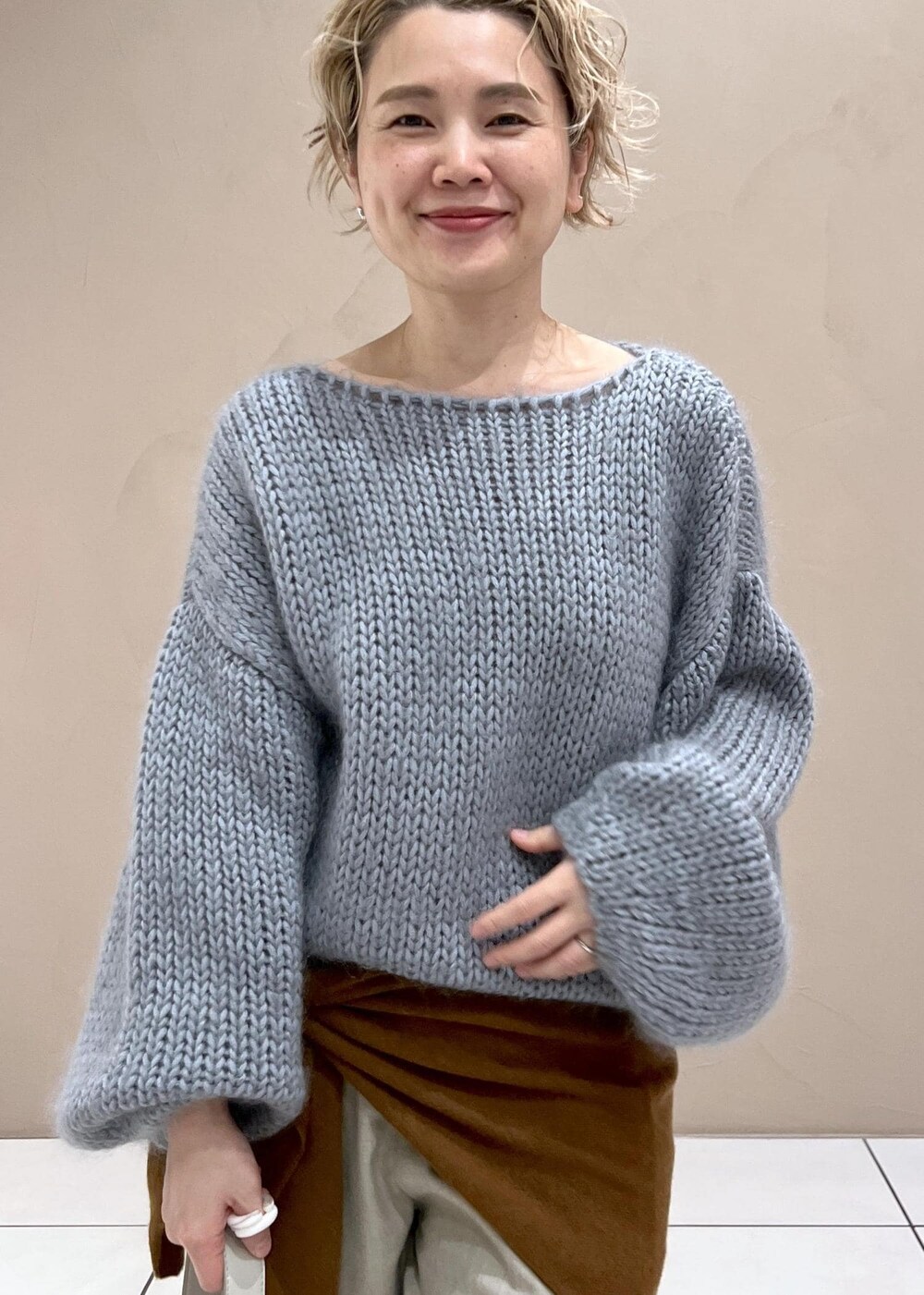 グレー系のショルダーバッグ、ベージュ系のスラックス、ブルー系のニット/セーターを着用したレディースの秋コーディネートの6枚目の写真