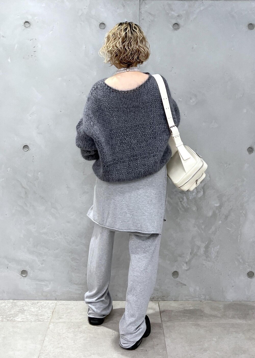 グレー系のニット/セーター、ホワイト系のボディバッグ/ウエストポーチ、グレー系の手袋を着用したレディースの秋コーディネートの4枚目の写真