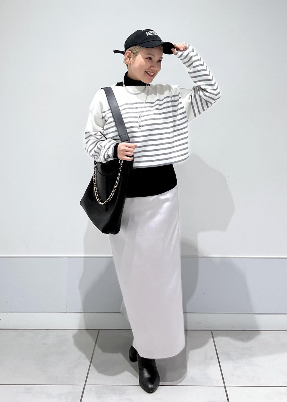 ブラック系のブーツ、ブラック系のTシャツ/カットソー、シルバー系のスカートを着用したレディースの冬コーディネートの3枚目の写真