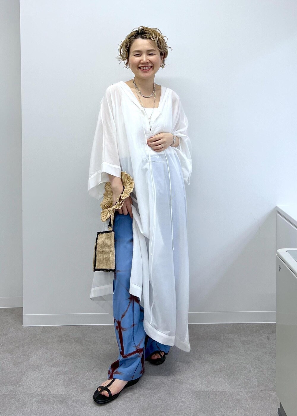 ブラック系のサンダル、ホワイト系のワンピース、ブルー系のその他パンツを着用したレディースの春コーディネートの2枚目の写真