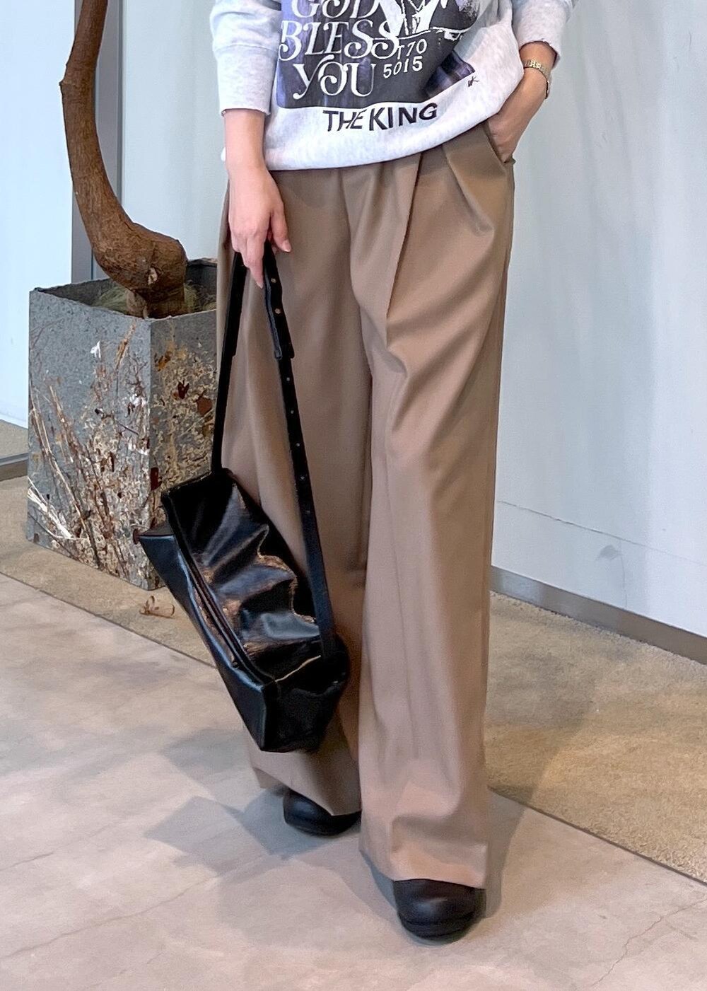 ベージュ系のスラックス、ブラック系のショルダーバッグ、ブラック系のスニーカーを着用したレディースの秋コーディネートの7枚目の写真