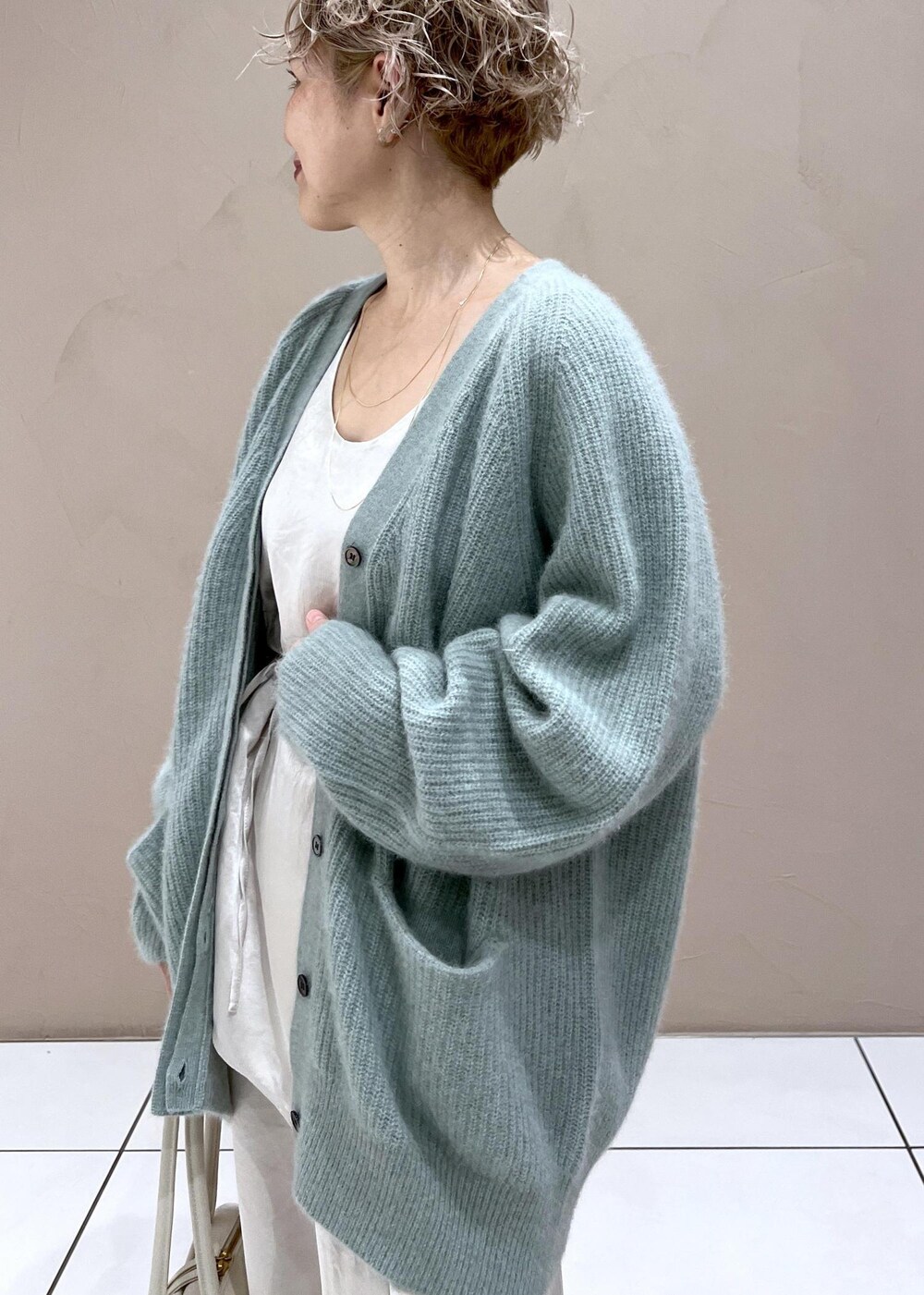 ホワイト系のTシャツ/カットソー、グリーン系のカーディガン/ボレロ、ホワイト系のカーゴパンツを着用したレディースの秋コーディネートの6枚目の写真