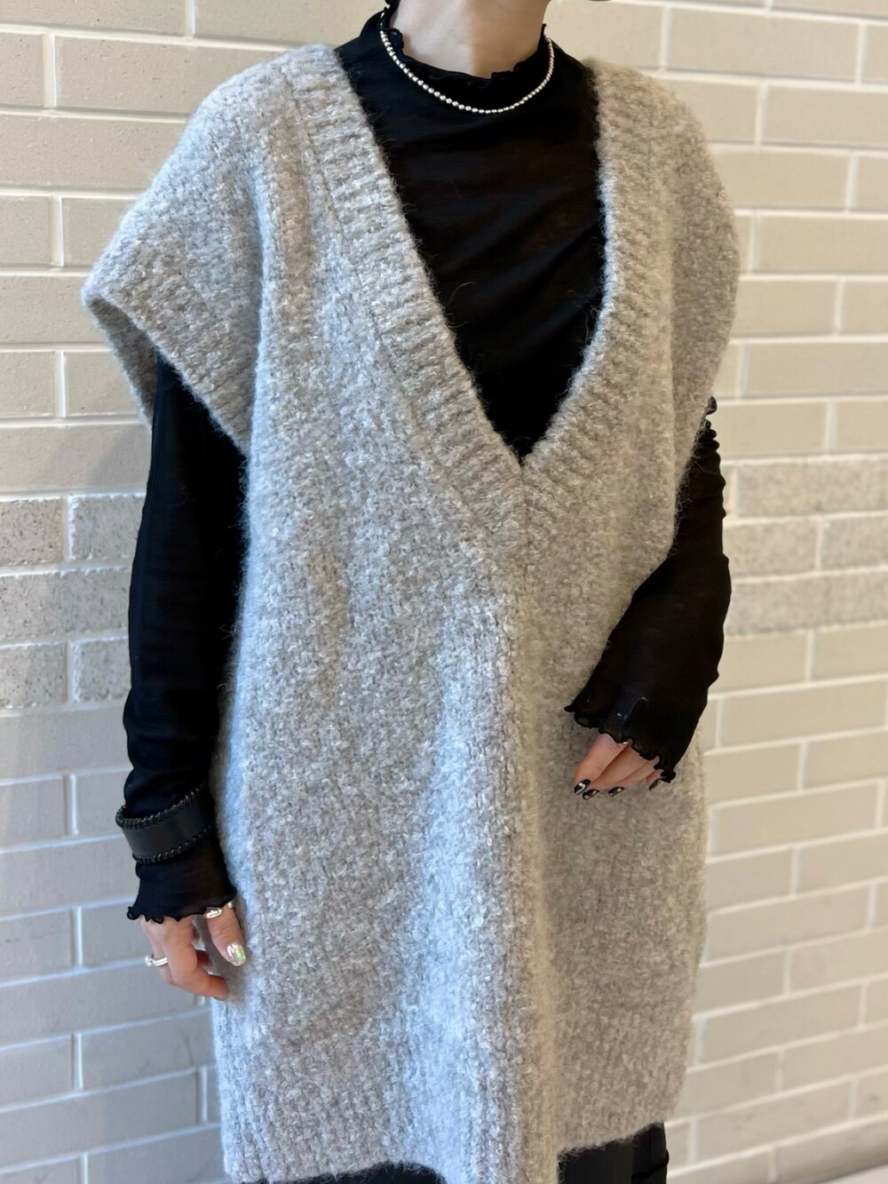 グレー系のニット/セーター、ブラック系のTシャツ/カットソー、ブラック系のスカートを着用したレディースの秋コーディネートの4枚目の写真