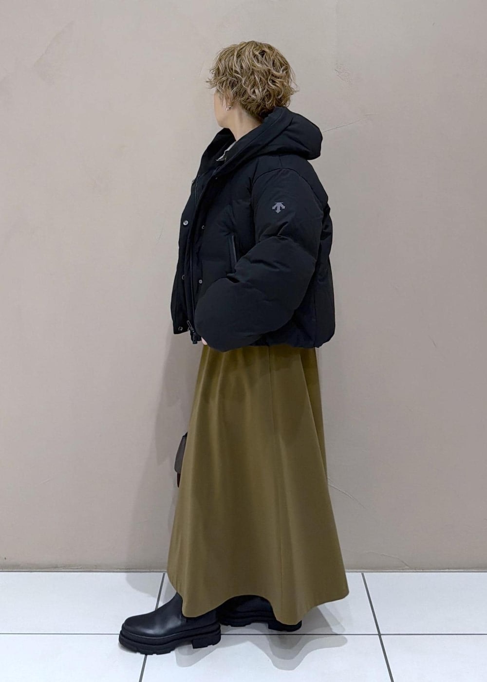 ブラウン系のスカート、ブラック系のダウンジャケット/コート、グレー系のニット/セーターを着用したレディースの冬コーディネートの4枚目の写真