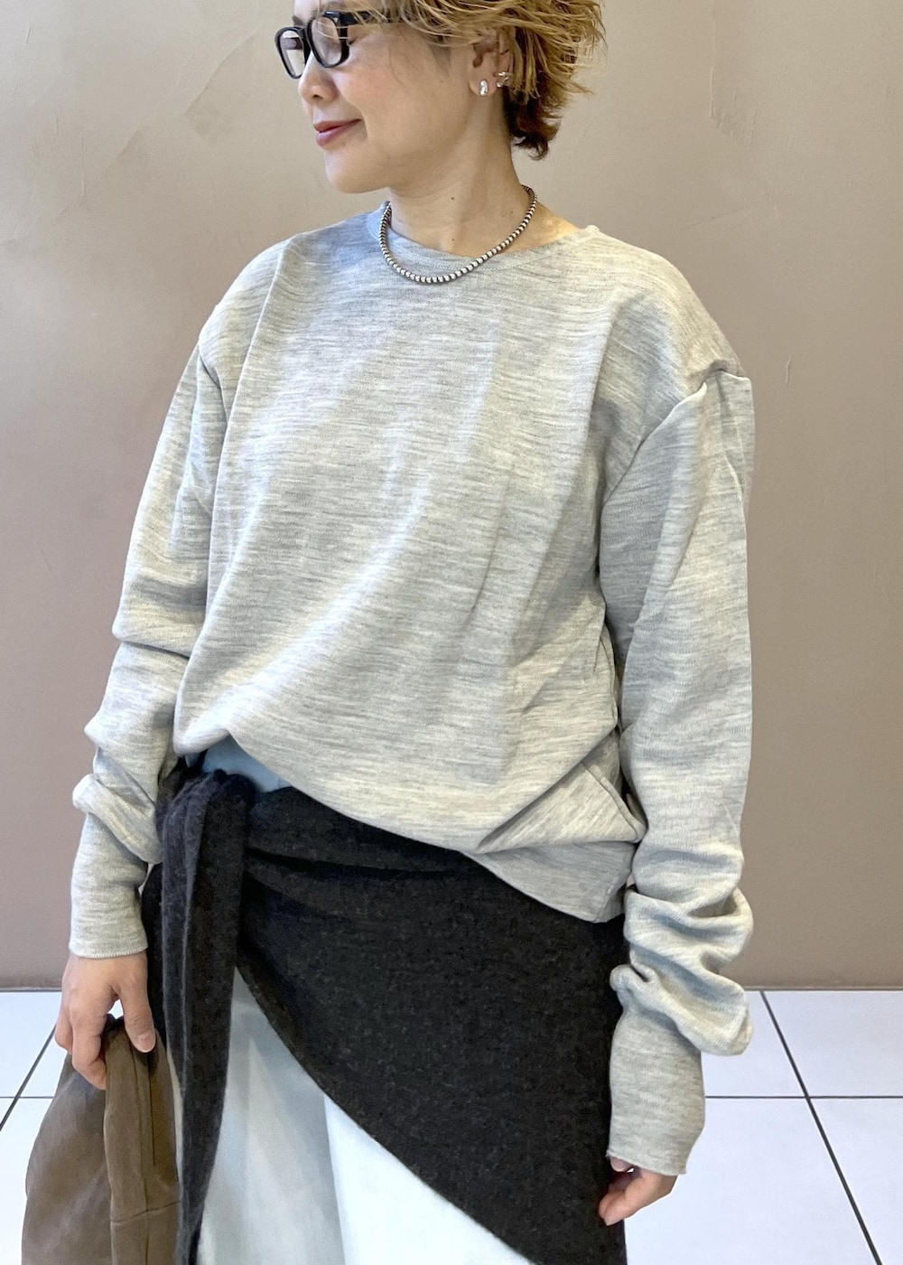 ブルー系のデニムパンツ、グレー系のハンドバッグ、ブラック系のパンプスを着用したレディースの秋コーディネートの7枚目の写真