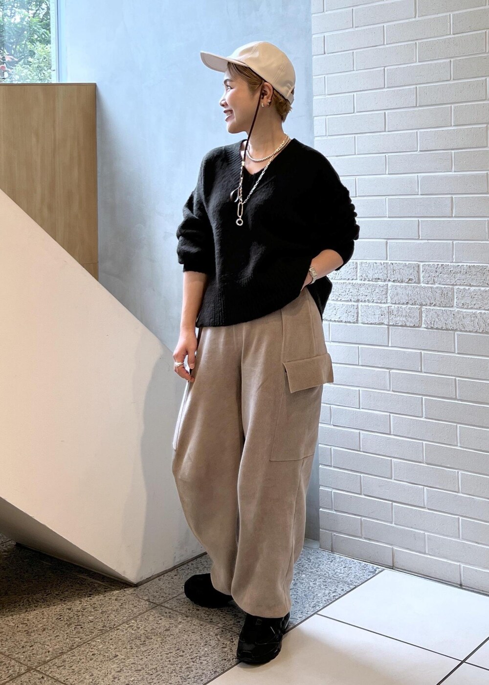 ホワイト系のピーコート、グレー系のカーゴパンツ、ブラウン系のニット/セーターを着用したレディースの秋コーディネートの3枚目の写真