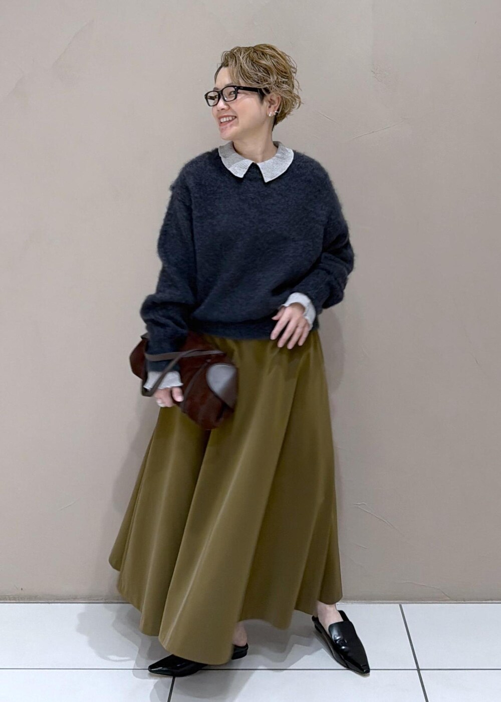 ブラウン系のスカート、ブラック系のローファー、グレー系のニット/セーターを着用したレディースの冬コーディネートの2枚目の写真