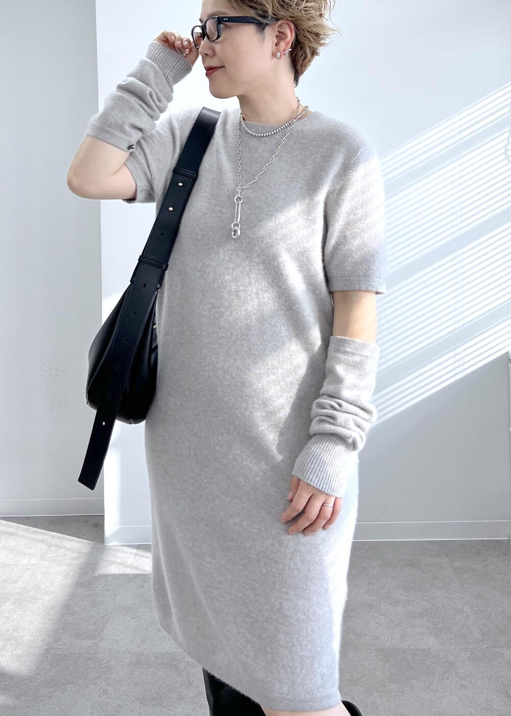 ブラック系のショルダーバッグ、ブラック系のブーツ、ベージュ系のワンピースを着用したレディースの秋コーディネートの4枚目の写真