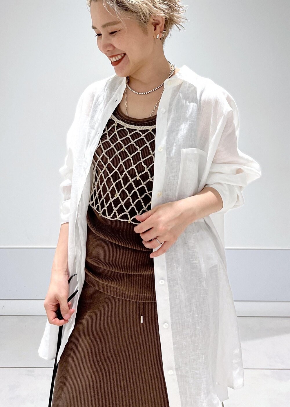 ブラック系のショルダーバッグ、ベージュ系のキャミソール、ブラウン系のタンクトップを着用したレディースの夏コーディネートの7枚目の写真