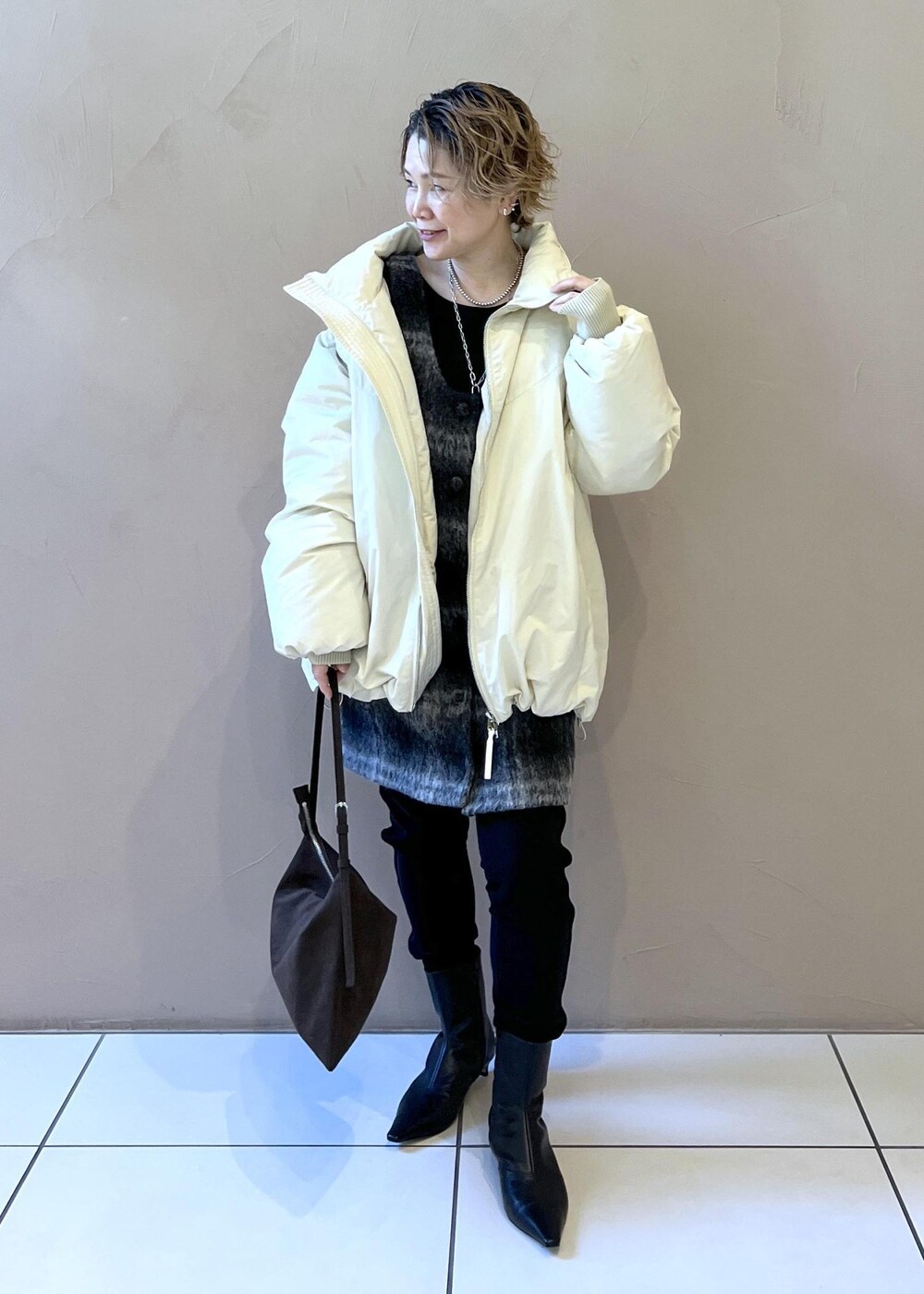 ホワイト系のダウンジャケット/コート、グレー系のジャンパースカート、ブラウン系のショルダーバッグを着用したレディースの秋コーディネートの4枚目の写真