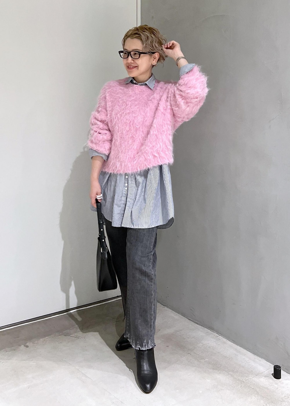 ブラック系のブーツ、ピンク系のニット/セーター、ブラック系のデニムパンツを着用したレディースの秋コーディネートの2枚目の写真