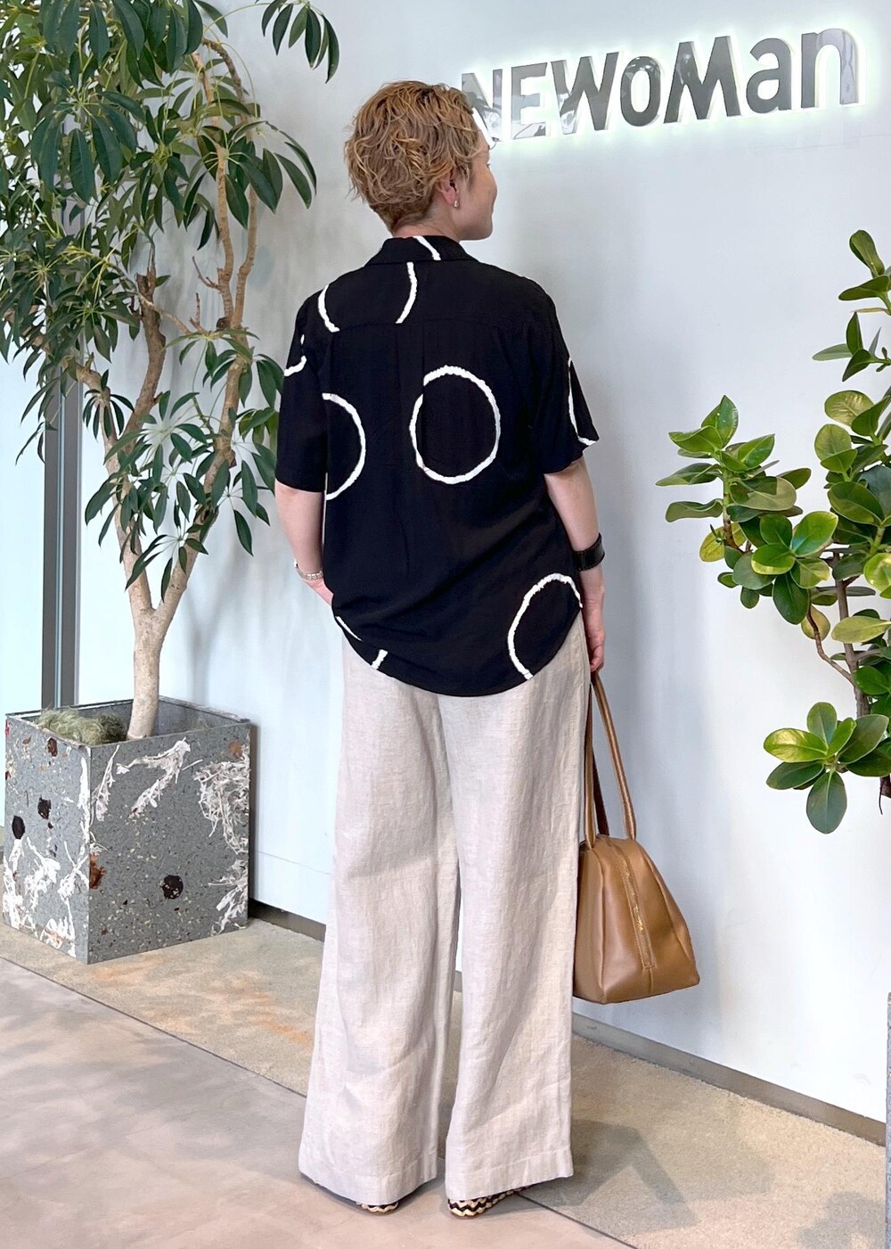 ブラウン系のボストンバッグ、ホワイト系のその他パンツ、ブラック系のサンダルを着用したレディースの夏コーディネートの4枚目の写真