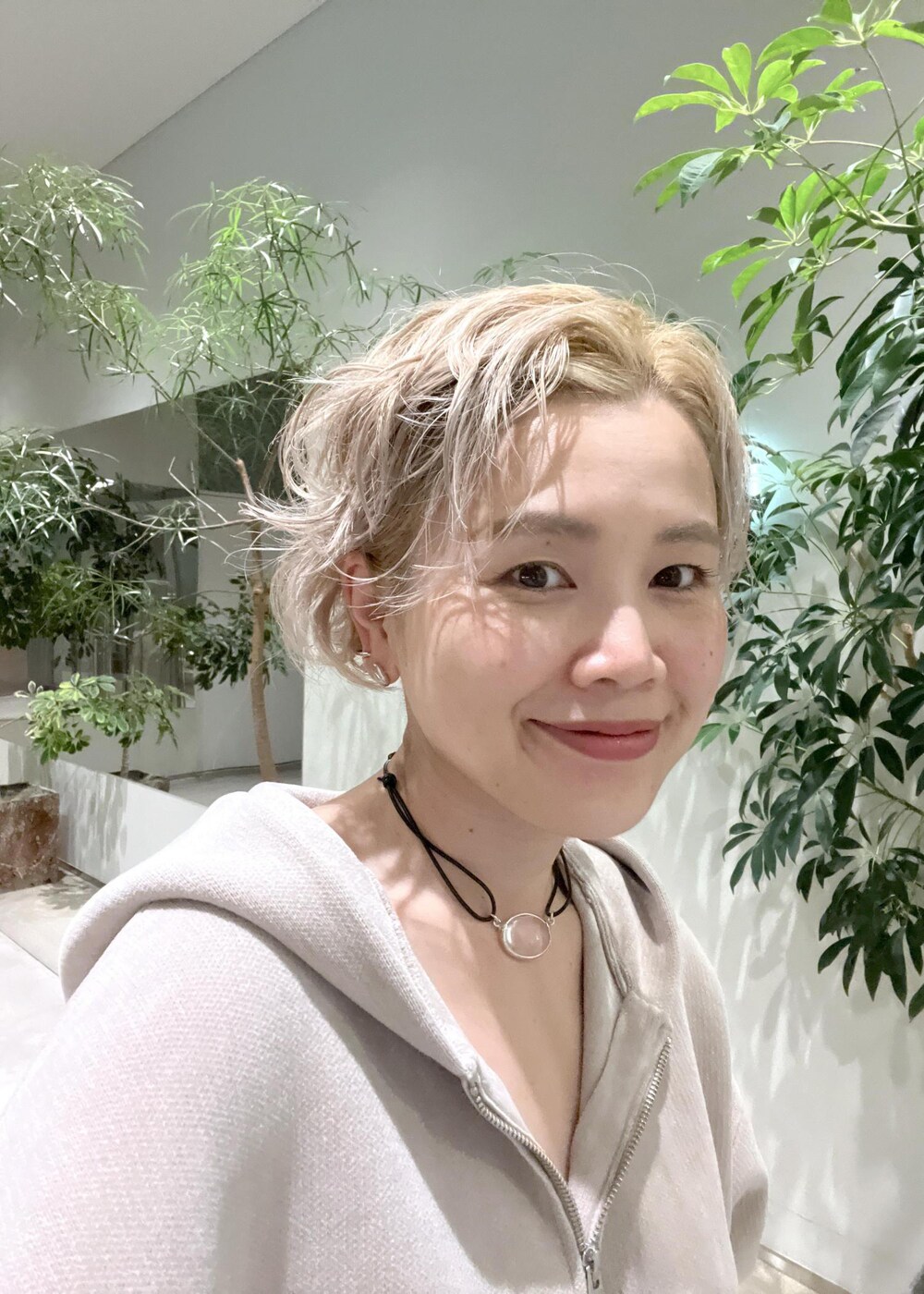 ベージュ系のパーカー、ホワイト系のボストンバッグ、ブラック系のブーツを着用したレディースの秋コーディネートの9枚目の写真