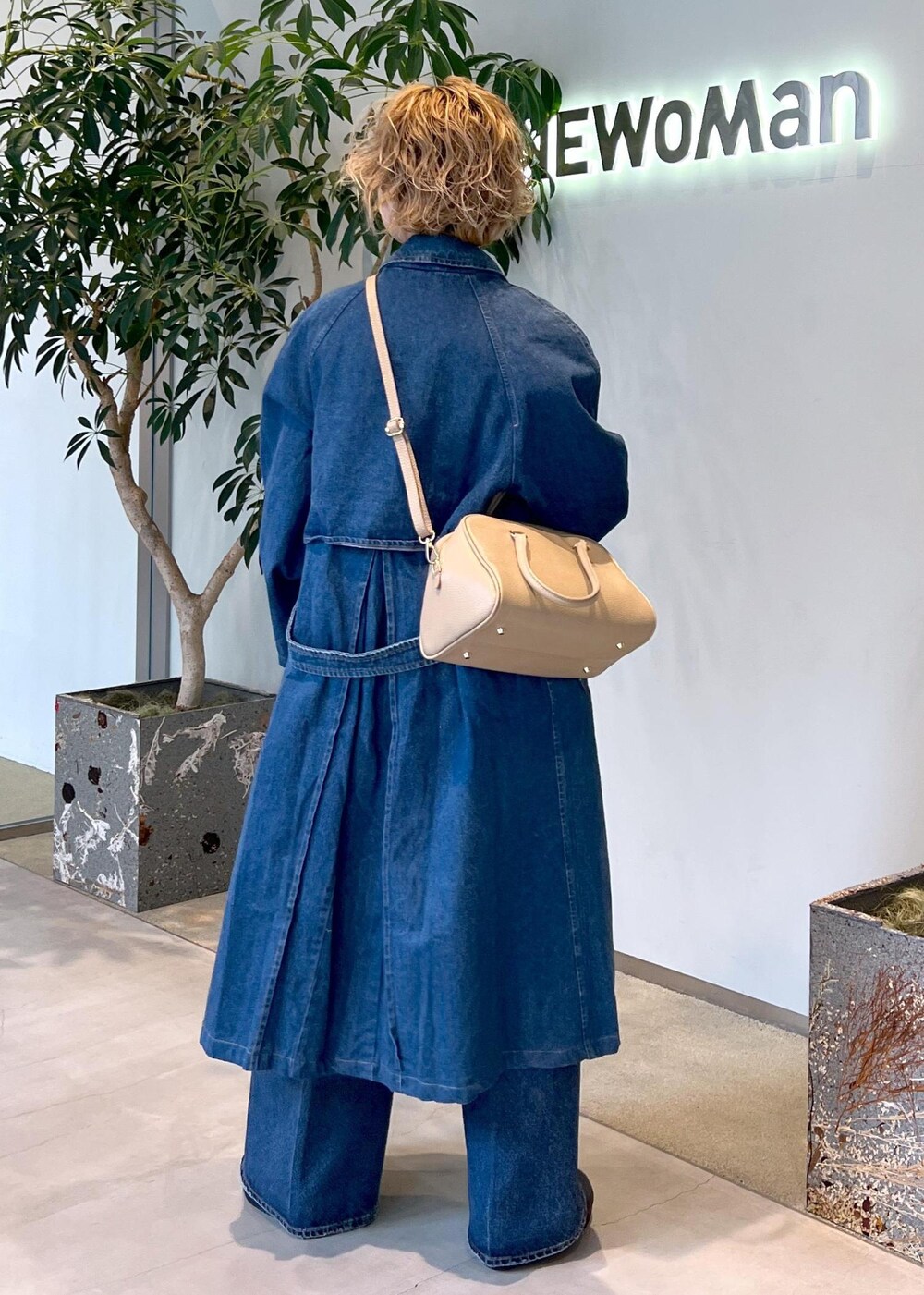 ベージュ系のボストンバッグ、ブルー系のデニムパンツ、ホワイト系のベストを着用したレディースの冬コーディネートの5枚目の写真