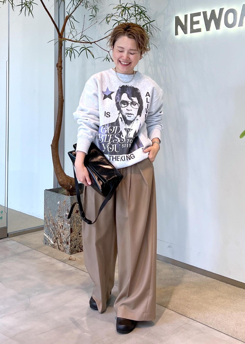 ベージュ系のスラックス、ブラック系のショルダーバッグ、ブラック系のスニーカーを着用したレディースの秋コーディネートの3枚目の写真