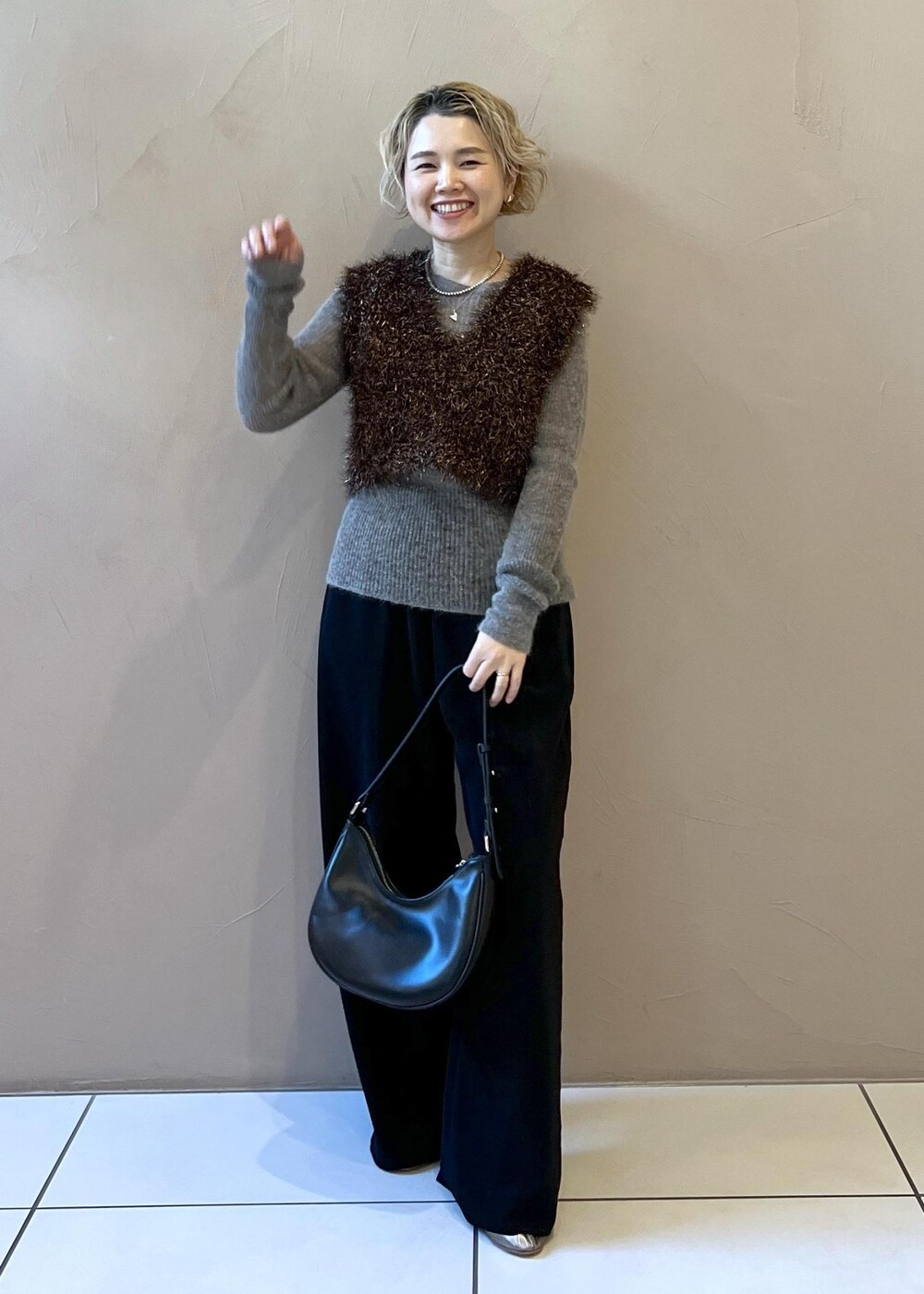 ブラック系のステンカラーコート、グレー系のニット/セーター、ブラック系のその他パンツを着用したレディースの冬コーディネートの3枚目の写真