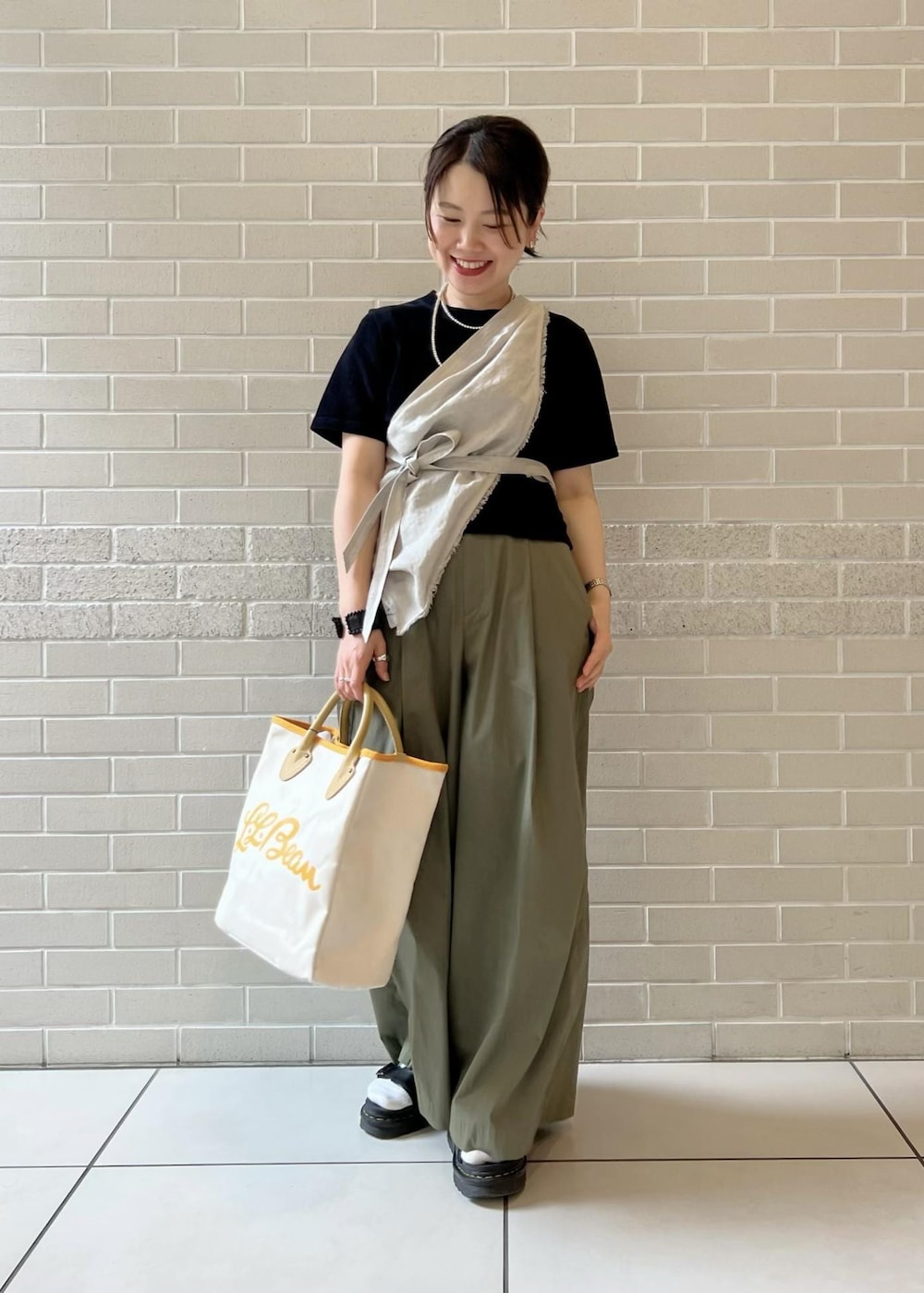 ホワイト系のトートバッグ、ブラック系のTシャツ/カットソー、グリーン系のその他パンツを着用したレディースの春コーディネートの3枚目の写真