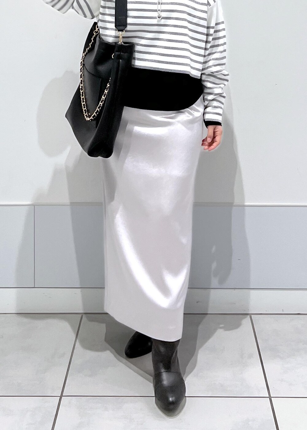 ブラック系のブーツ、ブラック系のTシャツ/カットソー、シルバー系のスカートを着用したレディースの冬コーディネートの5枚目の写真