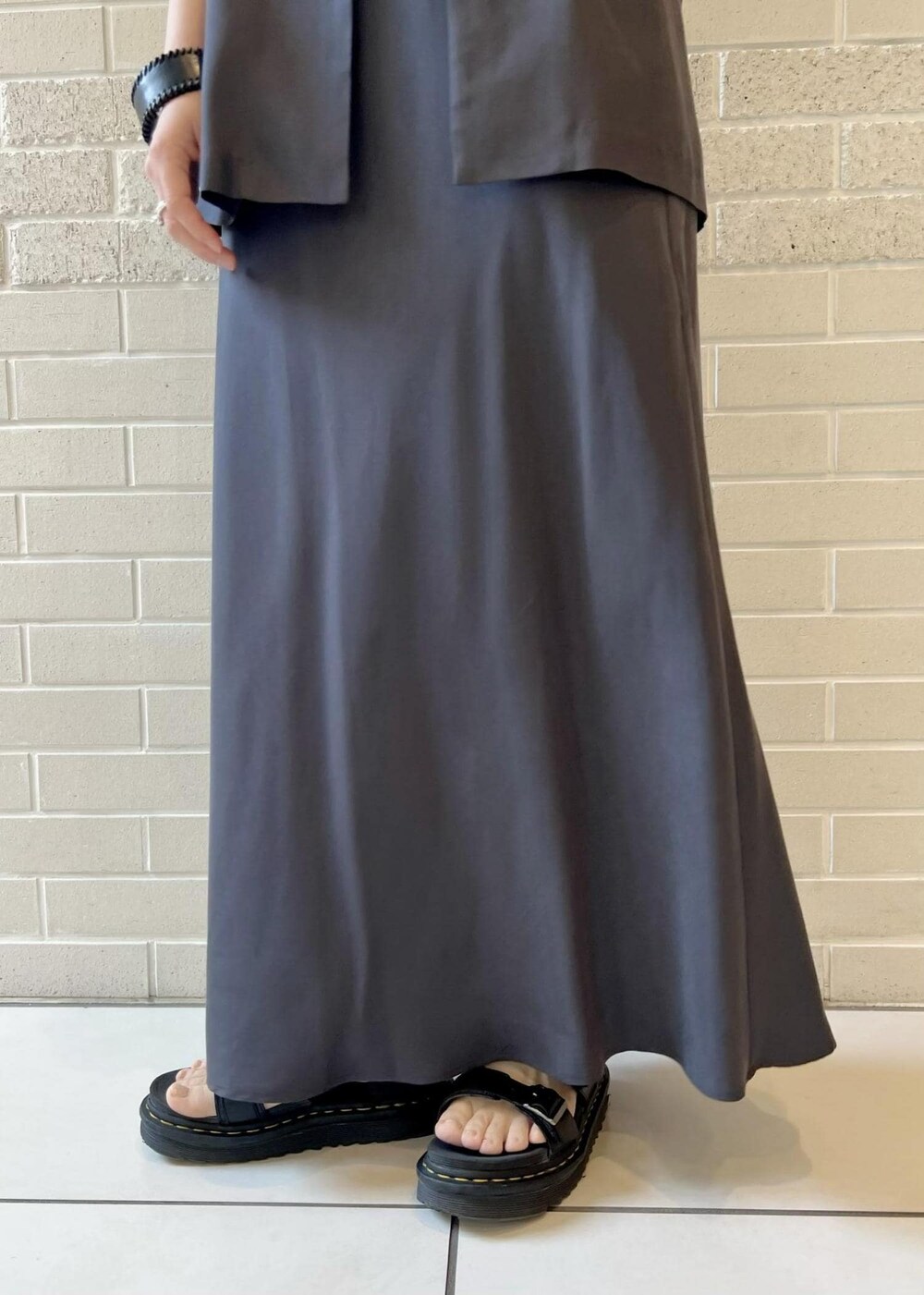 グレー系のスカート、ピンク系のカーディガン/ボレロ、ホワイト系のチューブトップを着用したレディースの春コーディネートの8枚目の写真