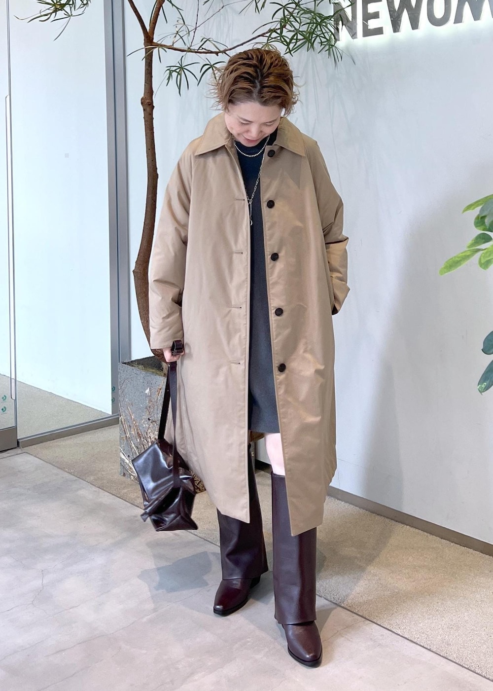 ブラウン系のブーツ、ブラウン系のショルダーバッグ、ベージュ系のダウンジャケット/コートを着用したレディースの秋コーディネートの2枚目の写真