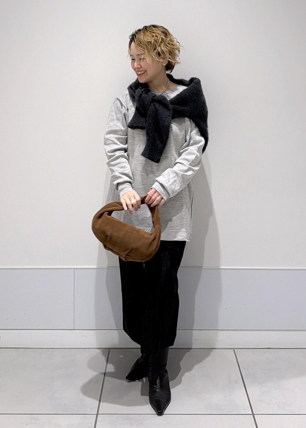 ブラック系のスカート、ブラウン系のハンドバッグ、ブラック系のブーツを着用したレディースの秋コーディネートの4枚目の写真