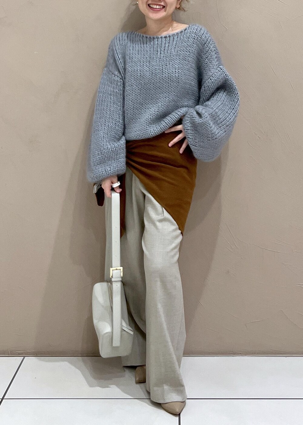 グレー系のショルダーバッグ、ベージュ系のスラックス、ブルー系のニット/セーターを着用したレディースの秋コーディネートの5枚目の写真