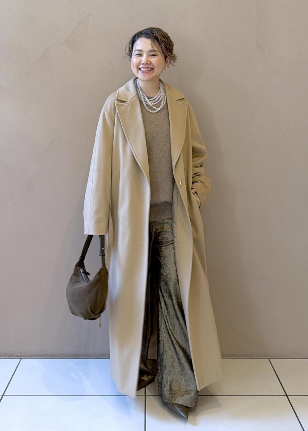 イエロー系のトレンチコート、ゴールド系のその他パンツ、ベージュ系のニット/セーターを着用したレディースの冬コーディネートの7枚目の写真