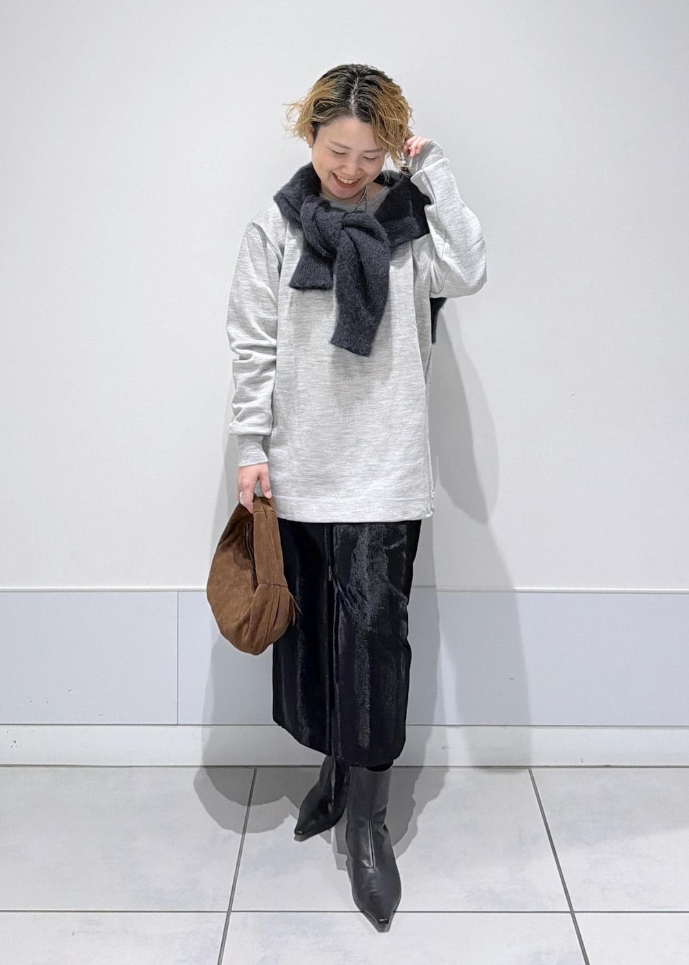 ブラック系のスカート、ブラウン系のハンドバッグ、ブラック系のブーツを着用したレディースの秋コーディネートの3枚目の写真