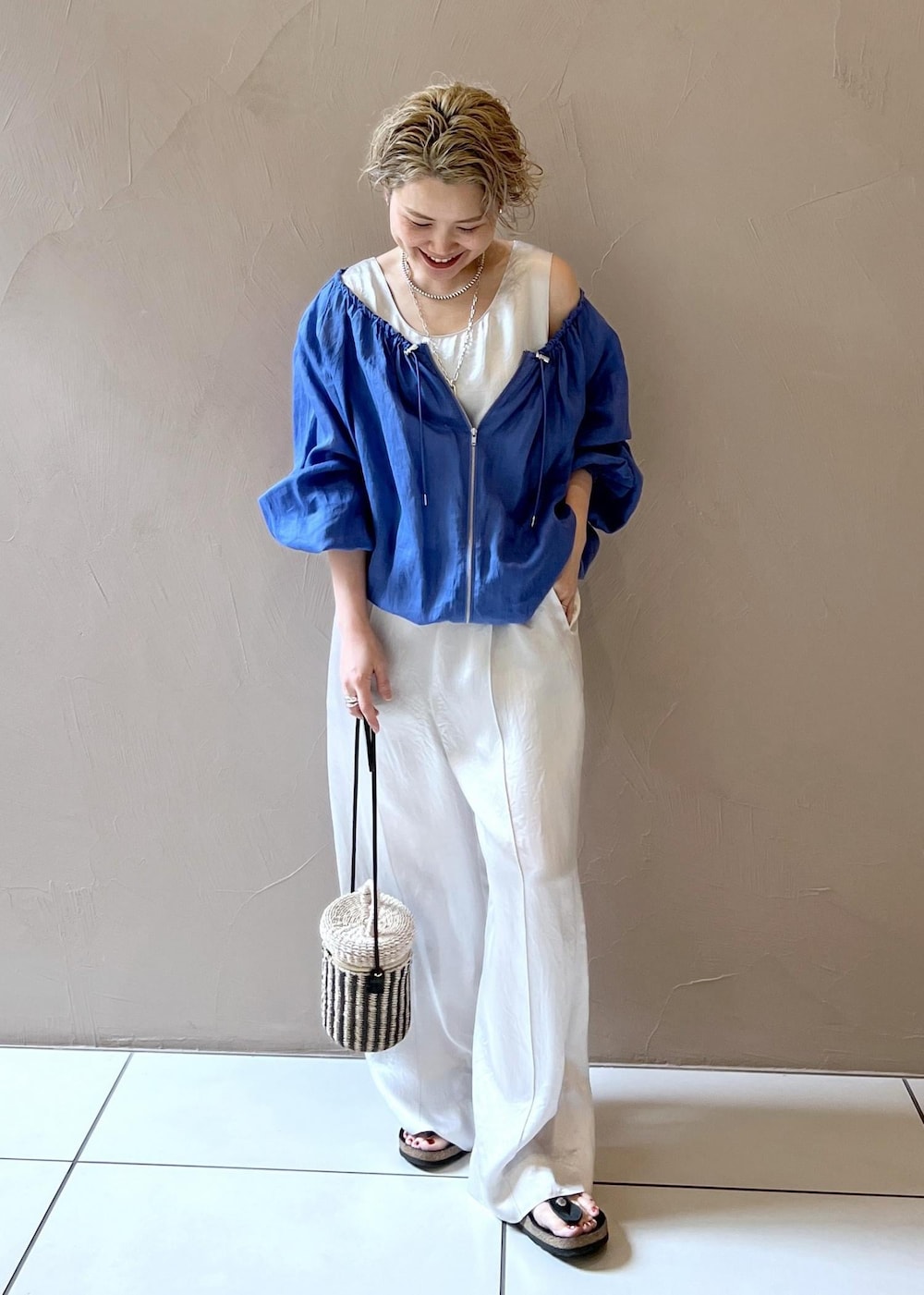 ホワイト系のショルダーバッグ、ブルー系のブルゾン、ホワイト系のつなぎ/オールインワンを着用したレディースの夏コーディネートの2枚目の写真