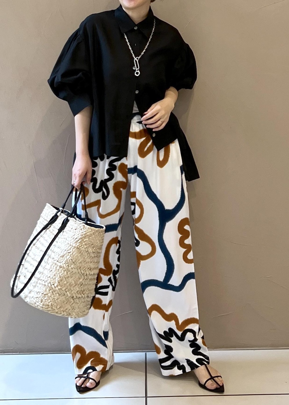 ブラック系のサンダル、ホワイト系のかごバッグ、ブラック系のシャツ/ブラウスを着用したレディースの春コーディネートの4枚目の写真