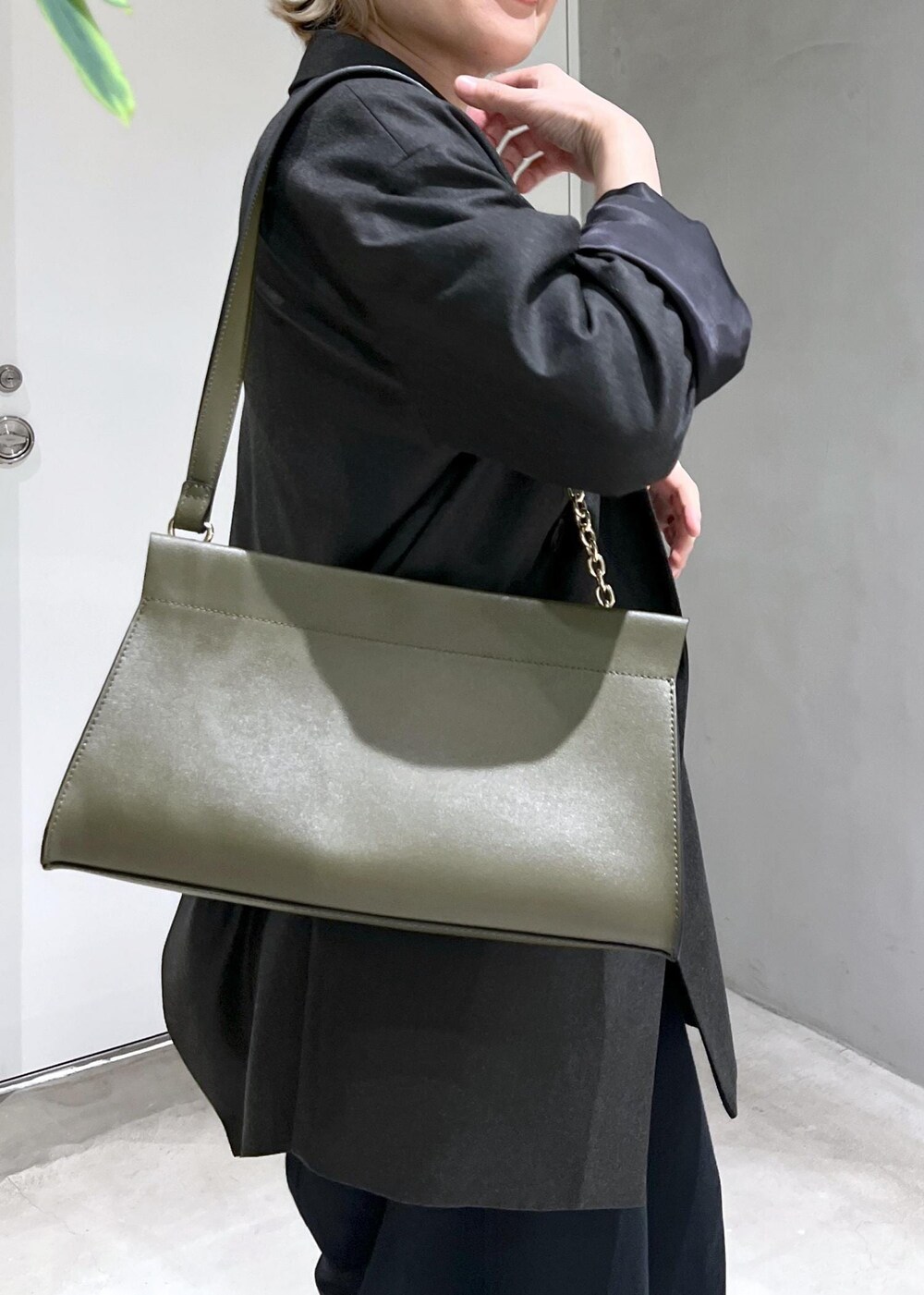 グリーン系のショルダーバッグ、ブラック系のスウェットパンツ、シルバー系のパンプスを着用したレディースの秋コーディネートの7枚目の写真