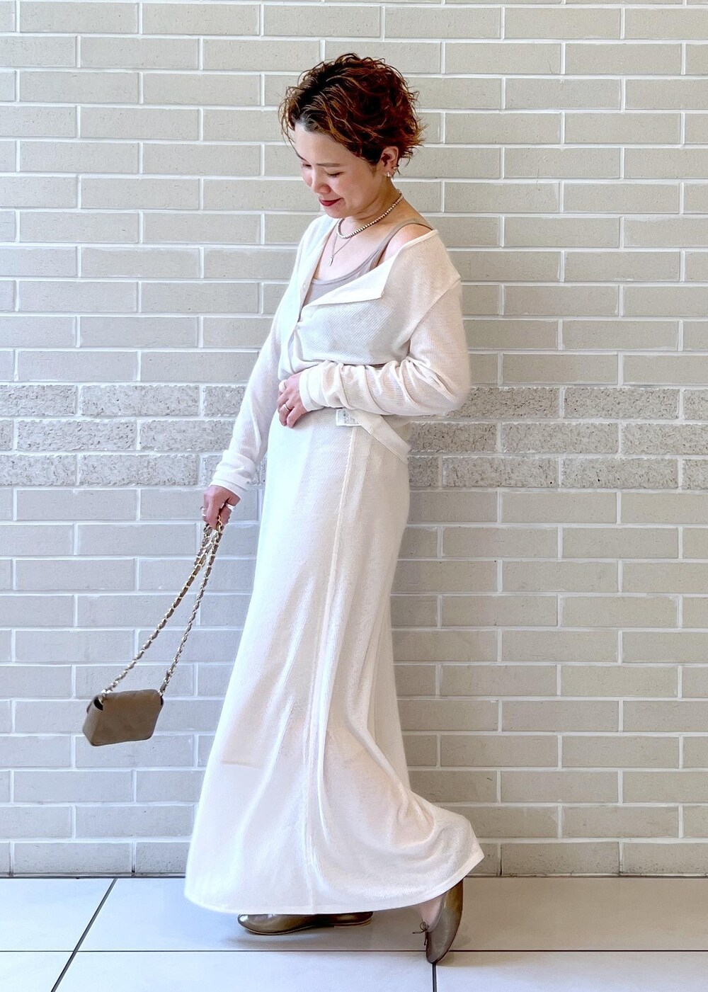 ホワイト系のスカート、ベージュ系のショルダーバッグ、ホワイト系のカーディガン/ボレロを着用したレディースの夏コーディネートの2枚目の写真