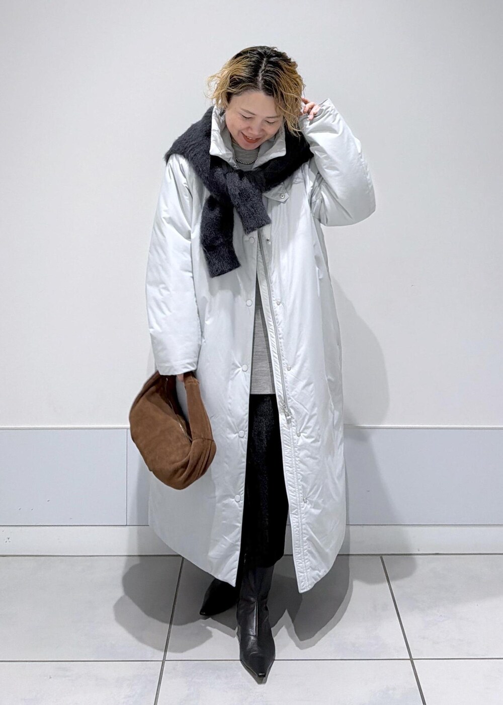 ブラック系のスカート、ブラウン系のハンドバッグ、グレー系のダウンジャケット/コートを着用したレディースの秋コーディネートの2枚目の写真