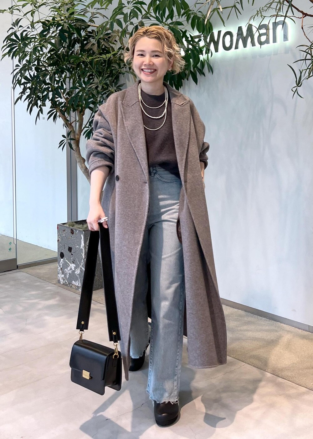 グレー系のニット/セーター、ブラック系のショルダーバッグ、ブラウン系のその他アウターを着用したレディースの秋コーディネートの4枚目の写真