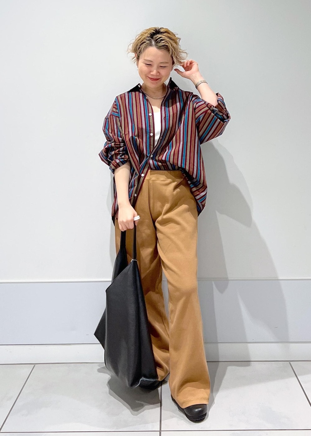 ブラック系のトートバッグ、ブラック系のスニーカー、ブラウン系のその他パンツを着用したレディースの冬コーディネートの2枚目の写真