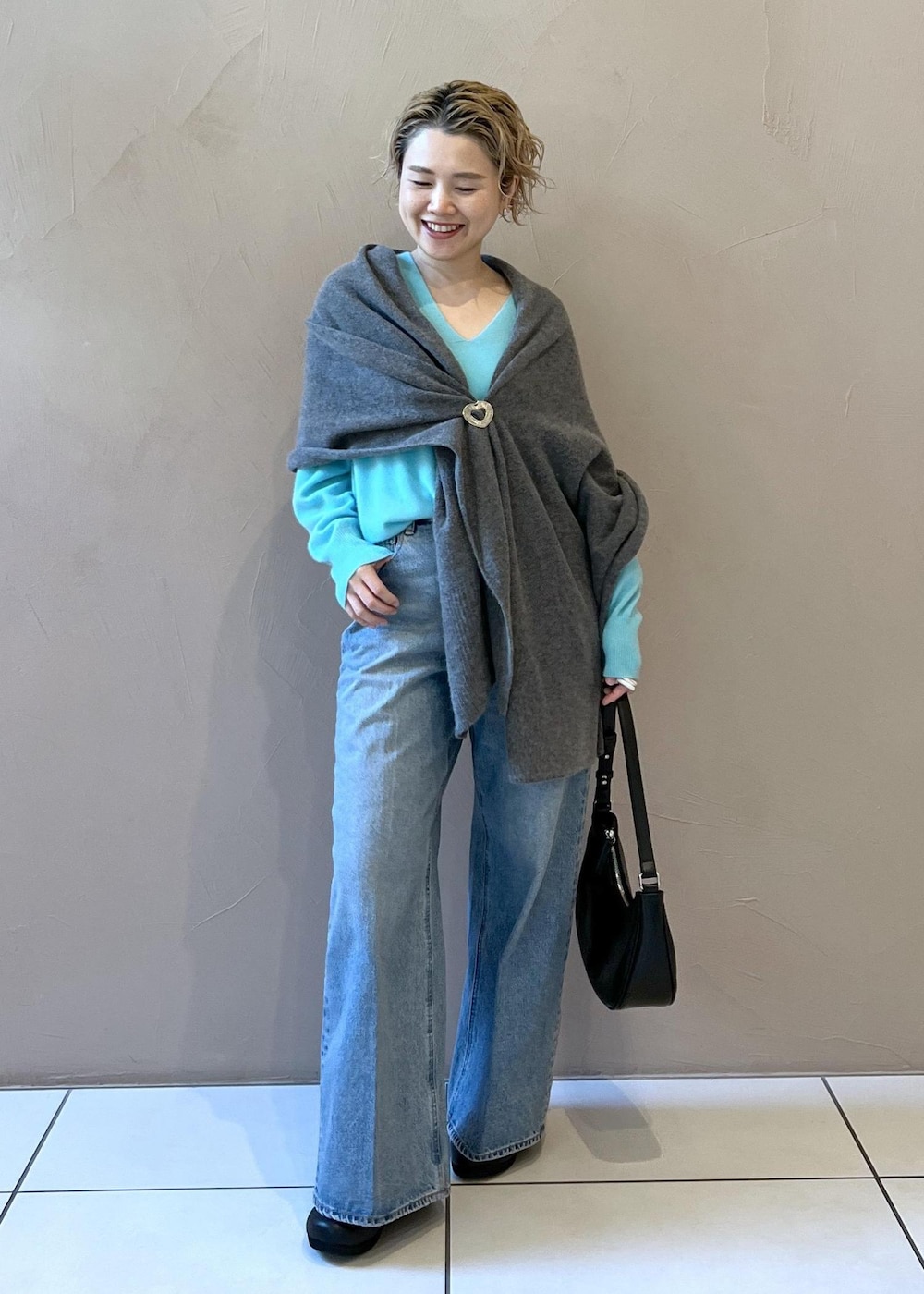 ブルー系のニット/セーター、ブルー系のデニムパンツ、ブラック系のスニーカーを着用したレディースの秋コーディネートの4枚目の写真