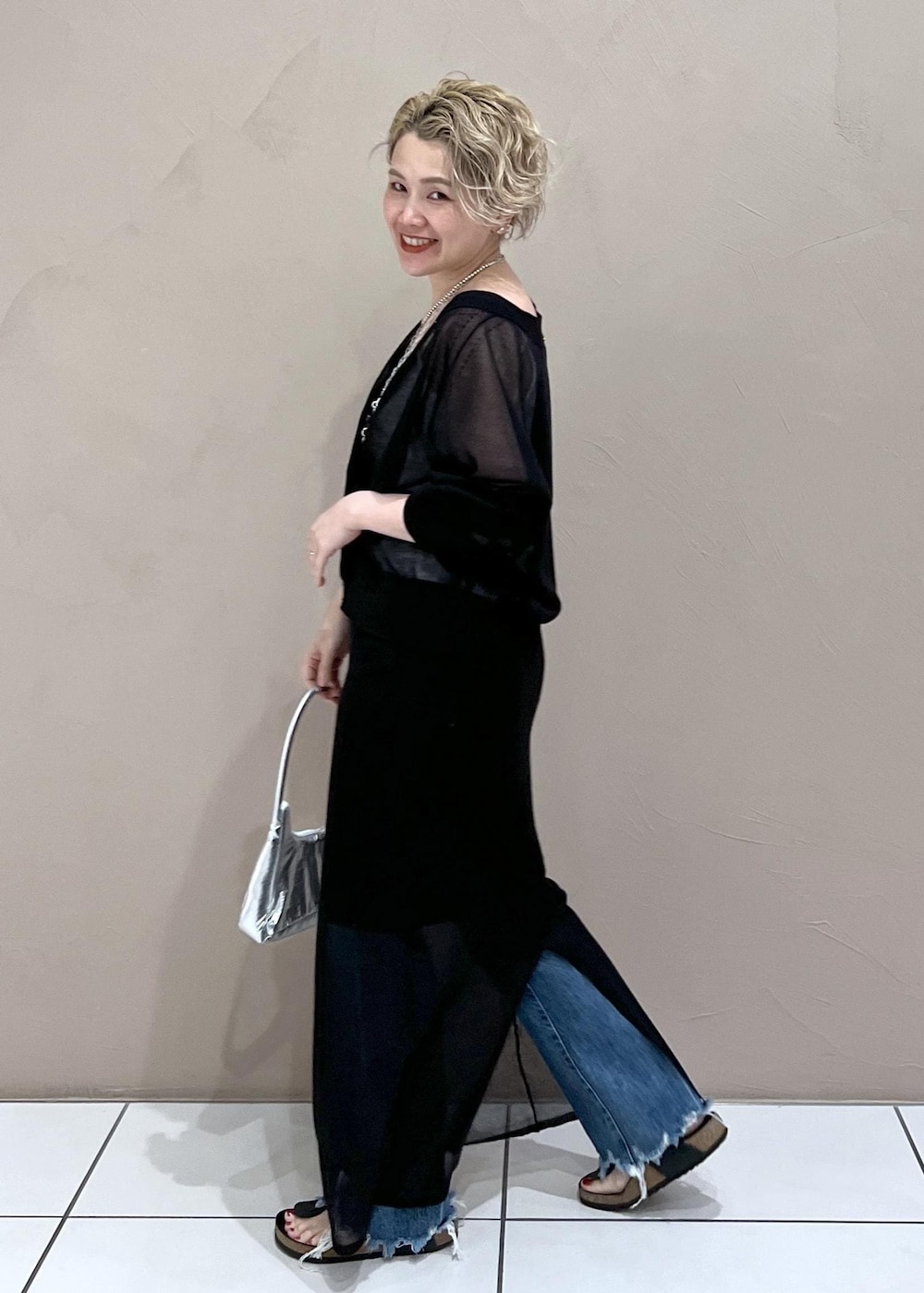 ホワイト系のタンクトップ、ブラック系のカーディガン/ボレロ、ブルー系のデニムパンツを着用したレディースの夏コーディネートの6枚目の写真