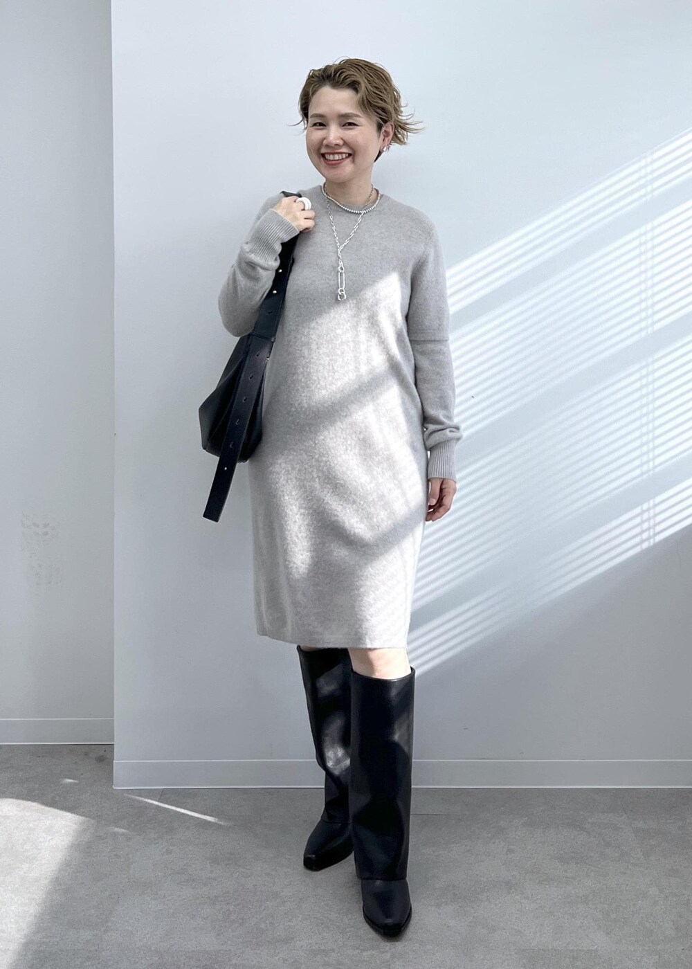 ブラック系のショルダーバッグ、ブラック系のブーツ、ベージュ系のワンピースを着用したレディースの秋コーディネートの7枚目の写真