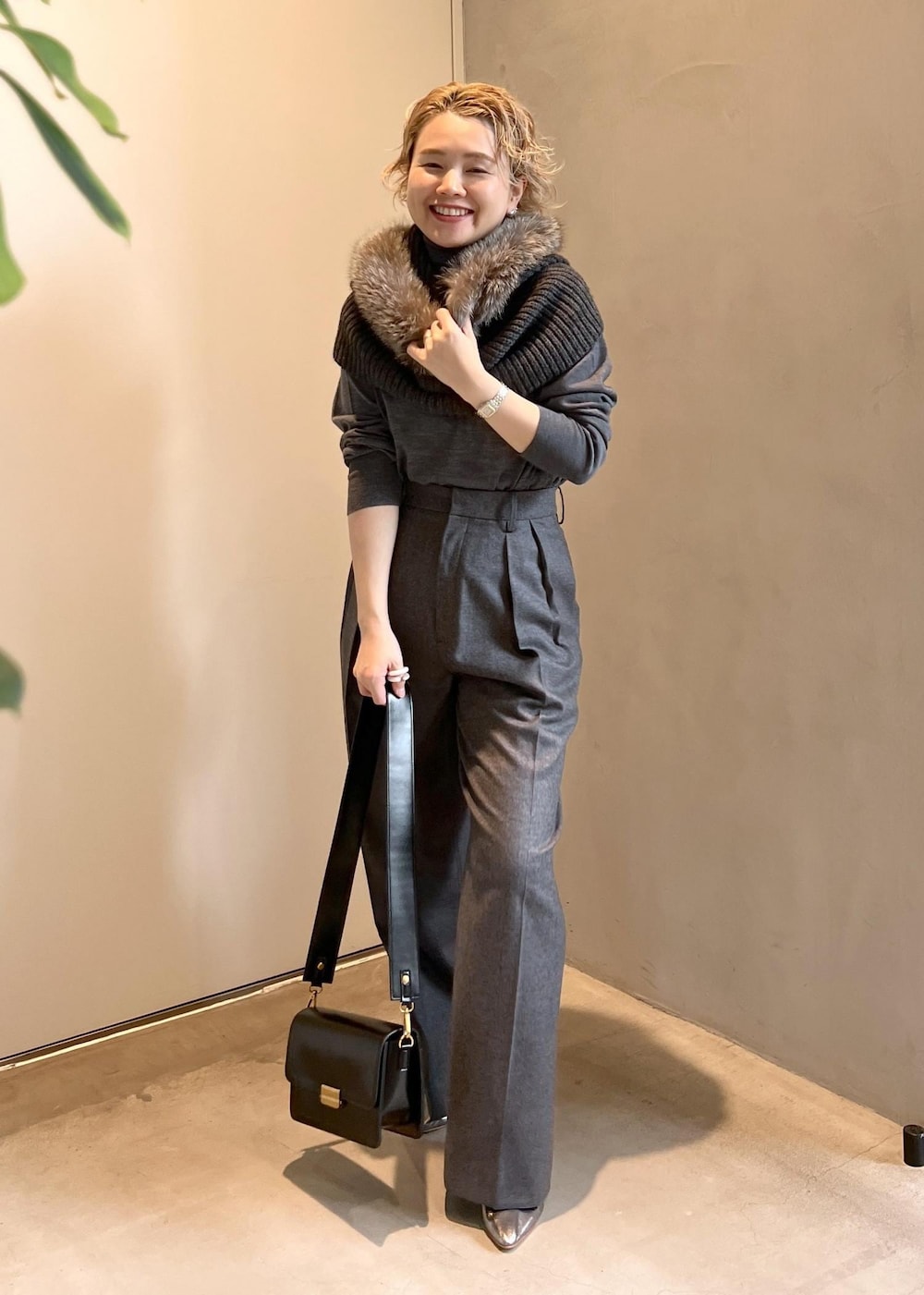 ブラック系のショルダーバッグ、グレー系のニット/セーター、グレー系のスラックスを着用したレディースの秋コーディネートの2枚目の写真