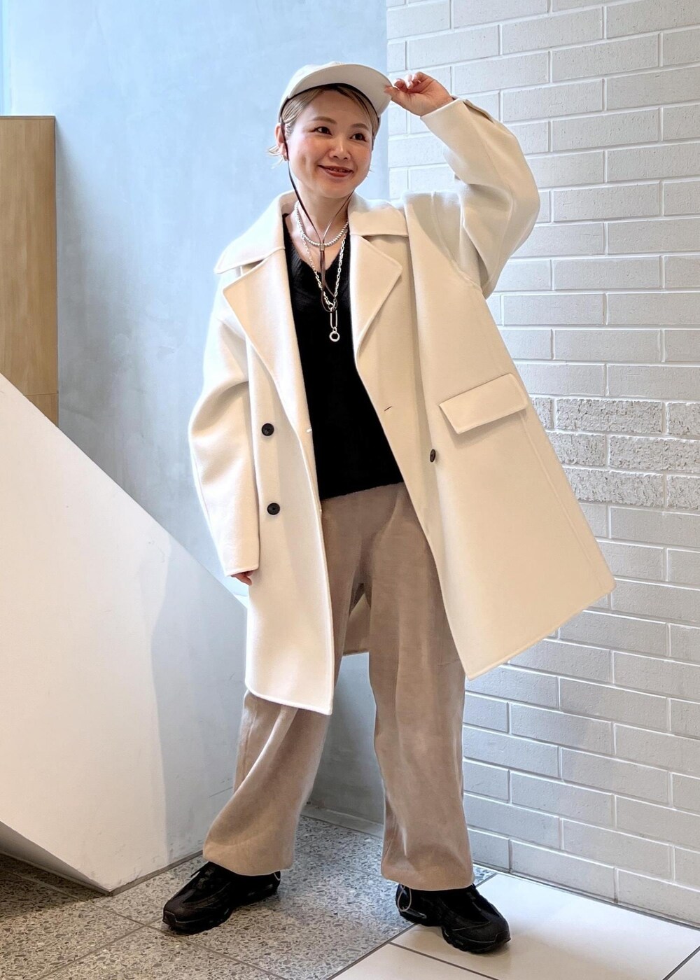 ホワイト系のピーコート、グレー系のカーゴパンツ、ブラウン系のニット/セーターを着用したレディースの秋コーディネートの7枚目の写真