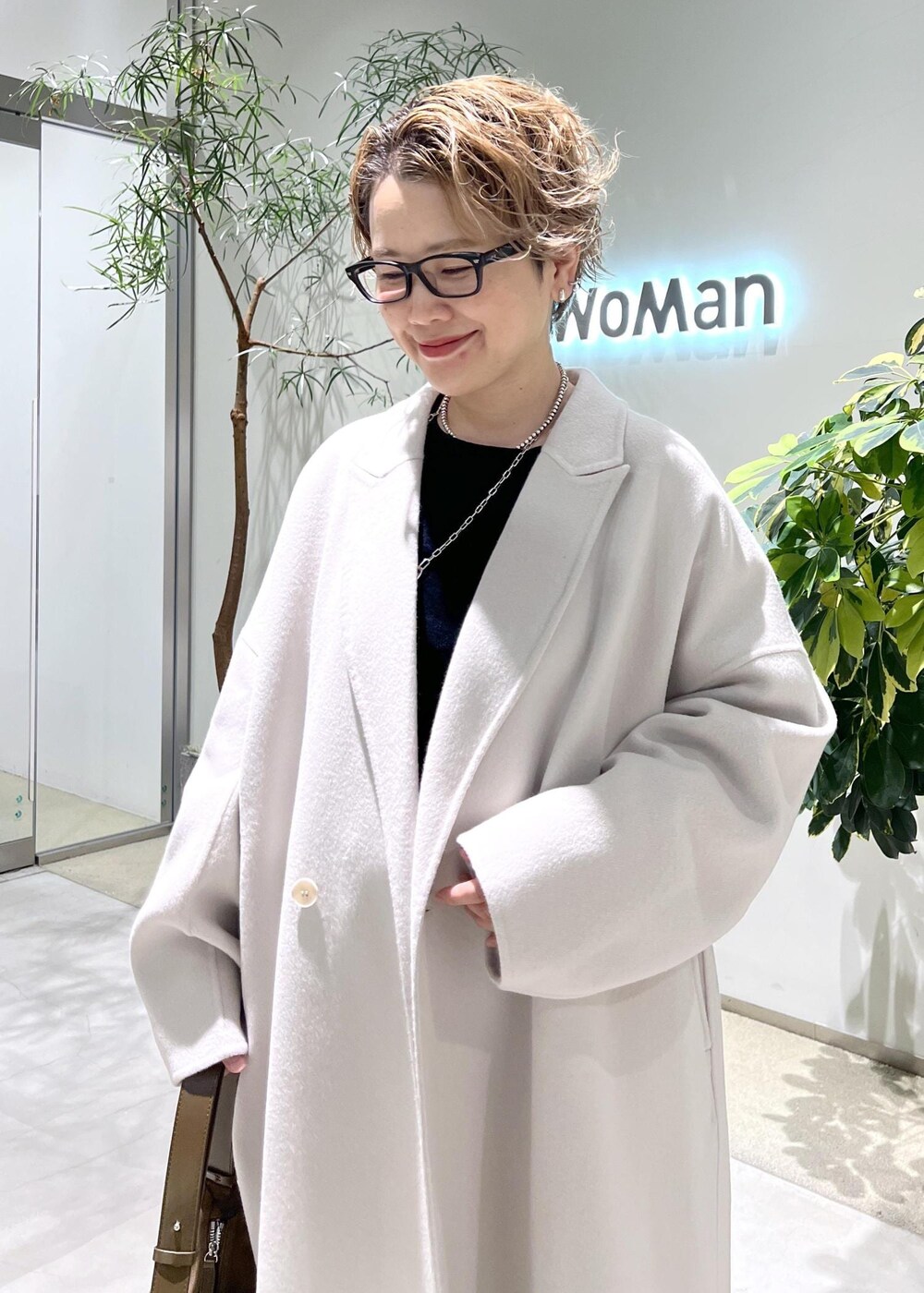 ホワイト系のチェスターコート、ブラック系のスウェット、ブラウン系のショルダーバッグを着用したレディースの秋コーディネートの8枚目の写真