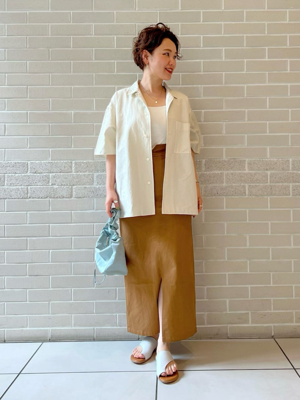 ホワイト系のシャツ/ブラウス、ホワイト系のキャミソール、イエロー系のスカートを着用したレディースの夏コーディネートの2枚目の写真