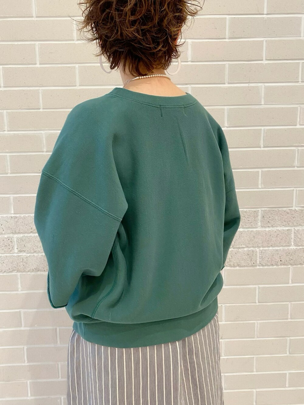 グリーン系のスウェット、ブラック系のワンピース、ブラウン系のサンダルを着用したレディースの春コーディネートの5枚目の写真