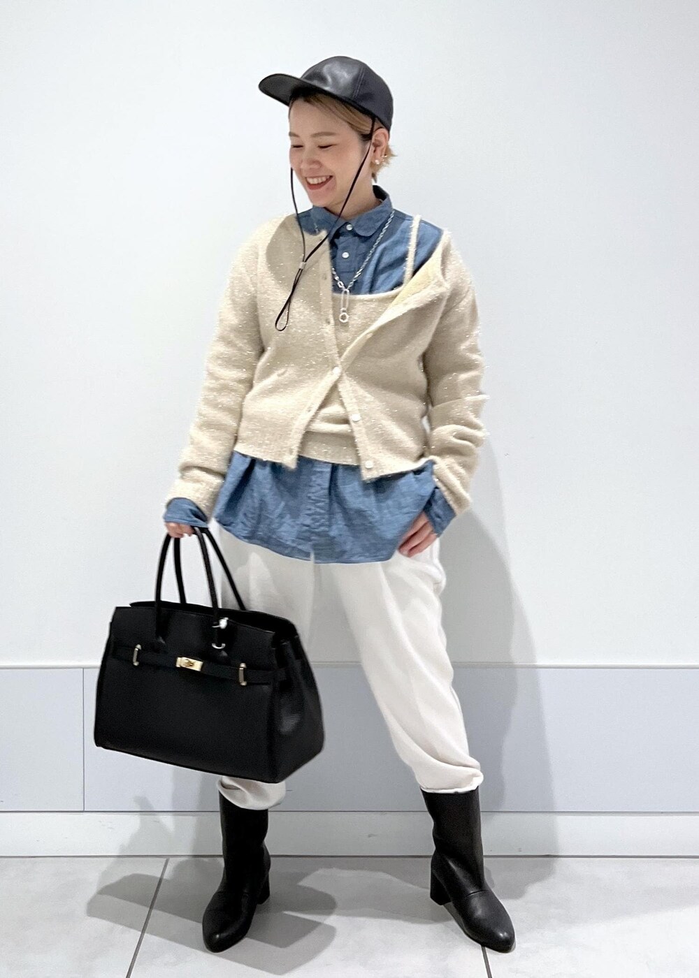 ゴールド系のカーディガン/ボレロ、ブラック系のハンドバッグ、ブラック系のブーツを着用したレディースの秋コーディネートの3枚目の写真