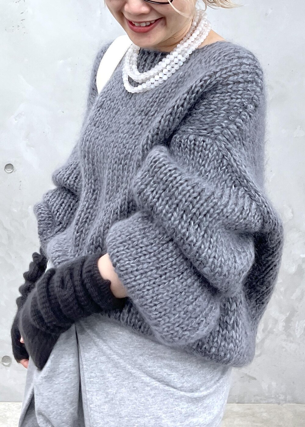 グレー系のニット/セーター、ホワイト系のボディバッグ/ウエストポーチ、グレー系の手袋を着用したレディースの秋コーディネートの5枚目の写真