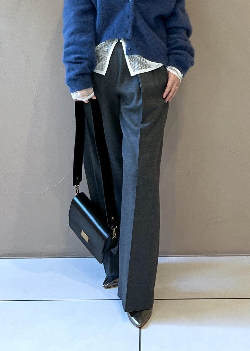 ブラック系のショルダーバッグ、ブルー系のカーディガン/ボレロ、グレー系のスラックスを着用したレディースの冬コーディネートの9枚目の写真