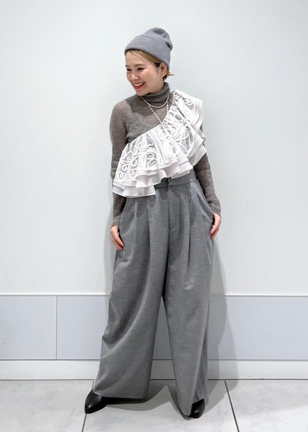 ブラック系のブーツ、グレー系のニット/セーター、ベージュ系のストール/ショールを着用したレディースの冬コーディネートの3枚目の写真