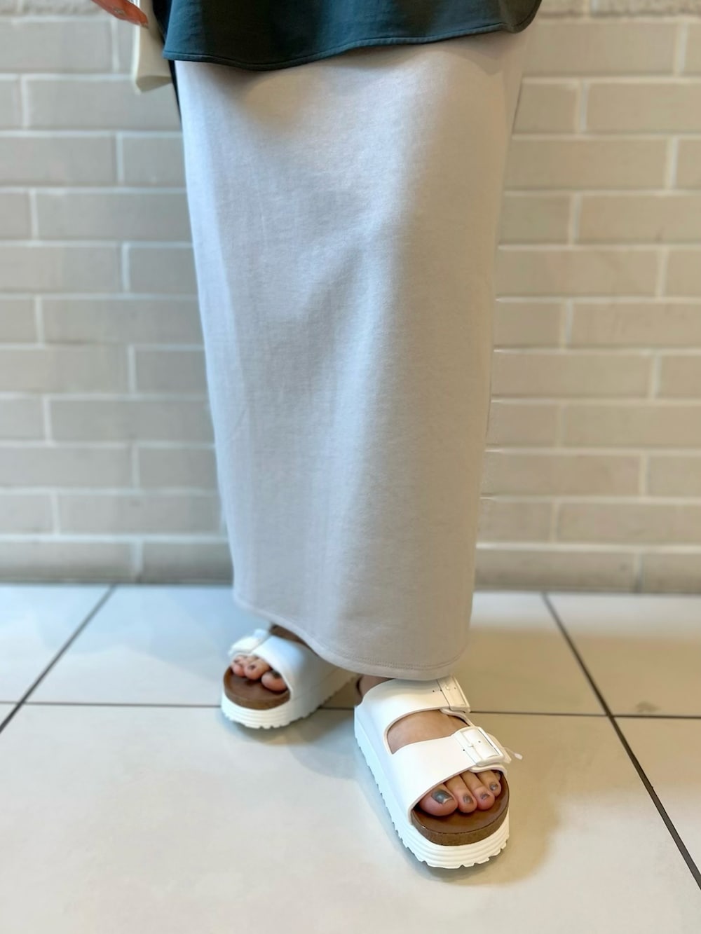 グリーン系のTシャツ/カットソー、ホワイト系のエコバッグ/サブバッグ、グレー系のスカートを着用したレディースの夏コーディネートの5枚目の写真