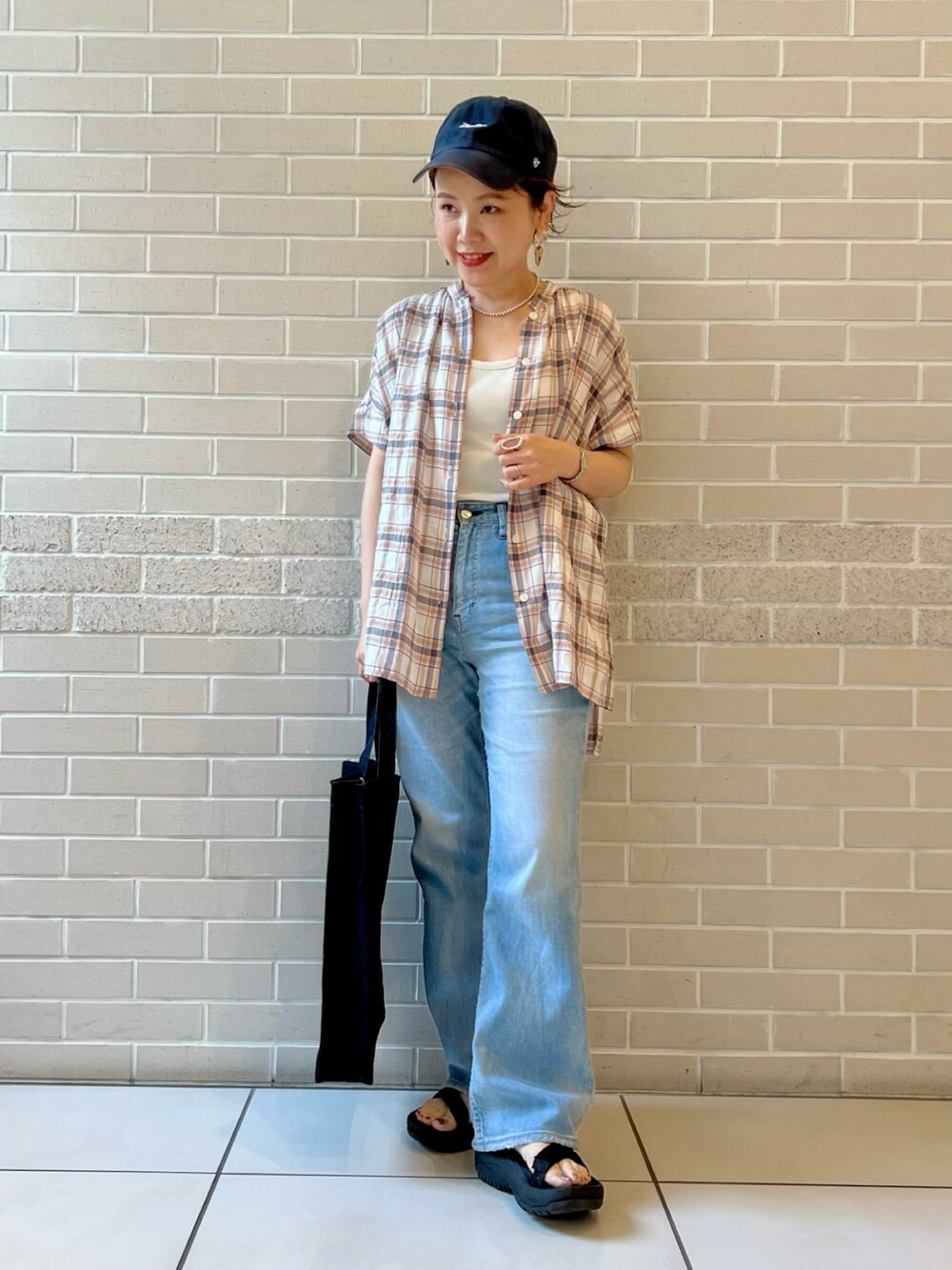 オレンジ系のシャツ/ブラウス、ブルー系のデニムパンツ、ブルー系のトートバッグを着用したレディースの夏コーディネートの2枚目の写真