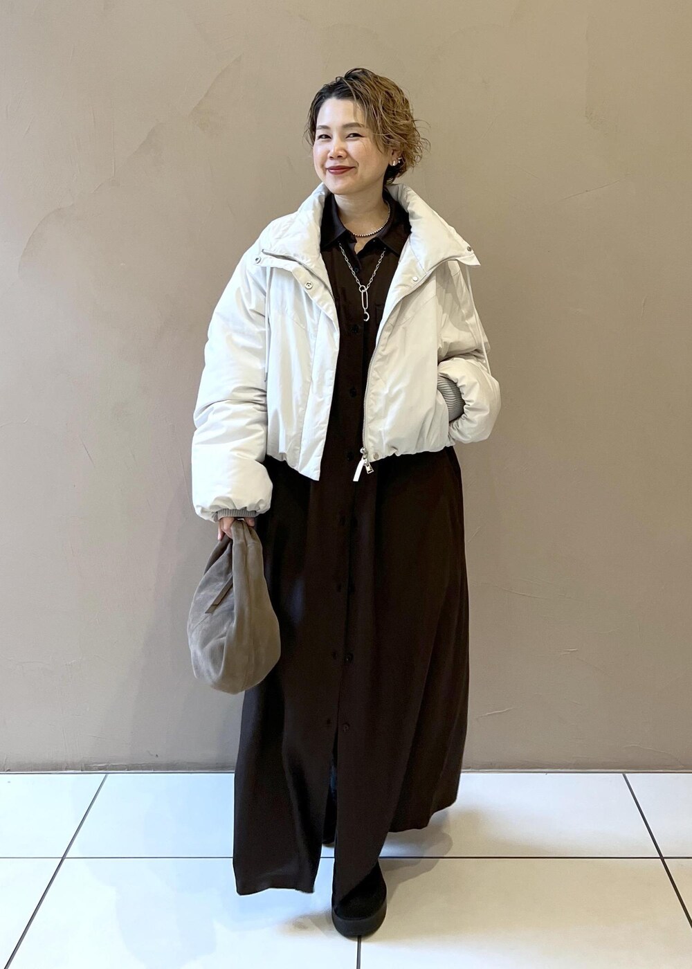 ホワイト系のダウンジャケット/コート、グレー系のハンドバッグ、グレー系のワンピースを着用したレディースの秋コーディネートの2枚目の写真